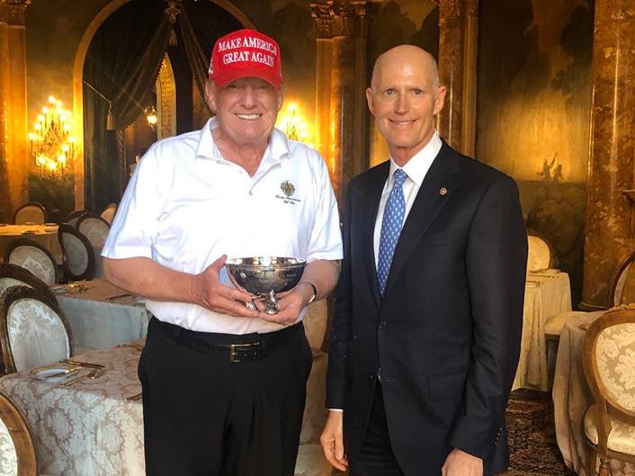 Sen. Rick Scott presents President Donald Trump with a tiny ceremonial bowl.