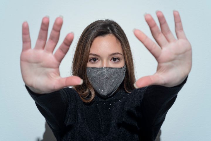 Portrait of worry young woman wearing face mask and showing stop gesture.studio shot.