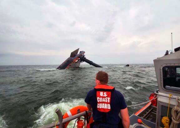 In this photo provided by the U.S. Coast Guard, A Coast Guard Station Grand Isle 45-foot Response Boat-medium boat crew member searches for survivors near the capsized SeaCor Power. The Seacor Power, an oil industry vessel, flipped over on April 13, 2021 in a microburst of dangerous wind and high seas.