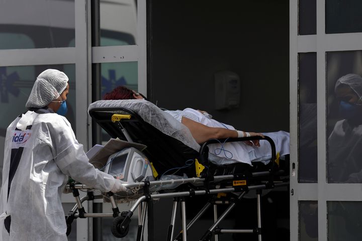 A healthcare worker pushes a patient suspected of having COVID-19 from an ambulance into the HRAN public hospital in Brasilia, Brazil, Wednesday, April 14, 2021. (AP Photo/Eraldo Peres)
