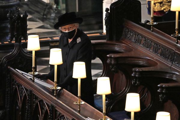 La reine Elizabeth II regarde les porteurs porter le cercueil du prince Philip.