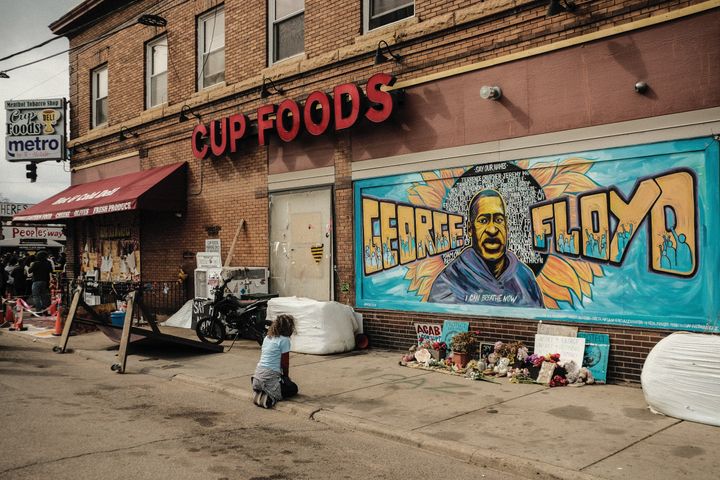 A woman pays respect to a mural of George Floyd by the Cup Foods where he was killed by Minneapolis Police Officer Derek Chauvin in Minneapolis, Minnesota.