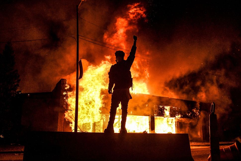 A protester stands in front of a burning building in Minneapolis on May 29, 2020, after the murder of George Floyd.
