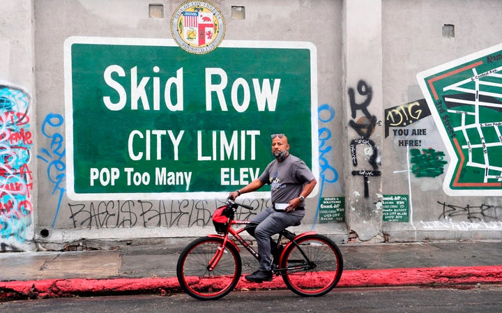 A cyclist rides past a Skid Row sign in Los Angeles on Feb. 1. A group of downtown businesses and residents sued local government officials over their handling of the area’s expanding homelessness crisis.