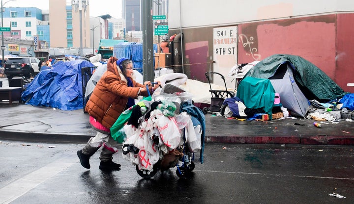 A woman pushes her belongings past a row of tents in Los Angeles on Feb. 1.&nbsp;At last count, more than 4,662 unhoused peop