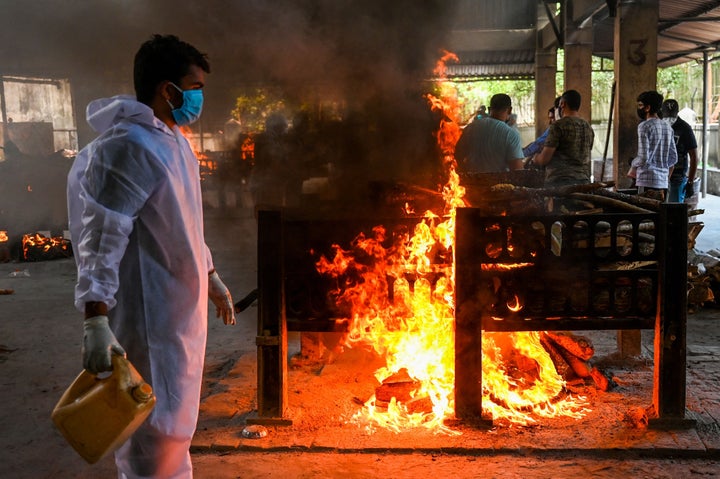 Crematorium staff light a pyre of a Covid-19 coronavirus victim, who died from a fire incident that killed 13 patients at the