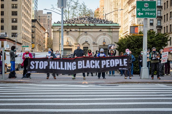 Un grupo de personas sostiene una pancarta que dice "dejar de matar en las personas negras" en una vigilia en Manhattan en honor a George Floyd.