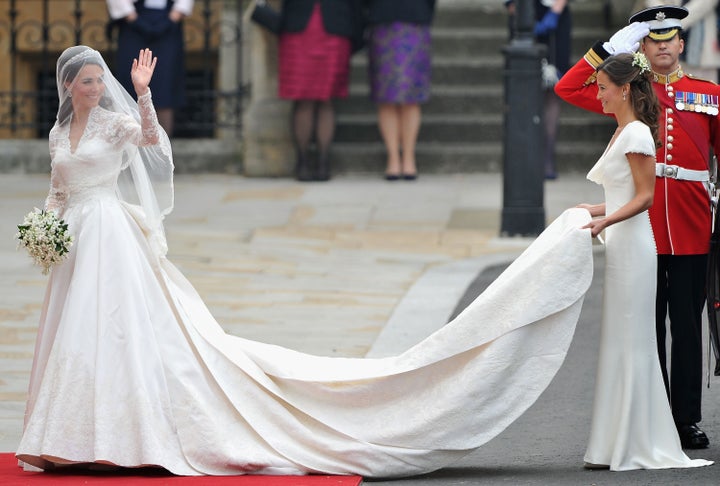 Kate waves to the crowds as her sister and maid of honor, Pippa Middleton, holds her dress before walking in to Westminster Abbey.