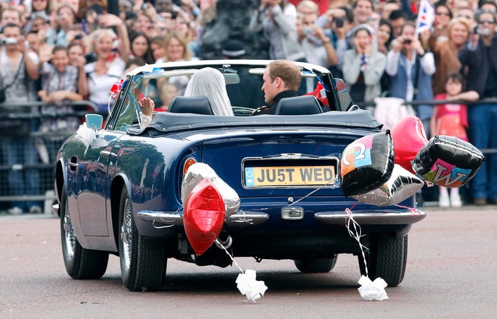 Les jeunes mariés quittent le palais de Buckingham pour se rendre à Clarence House, au volant de l'Aston Martin Volante 1969 du prince Charles, après leur réception de mariage.