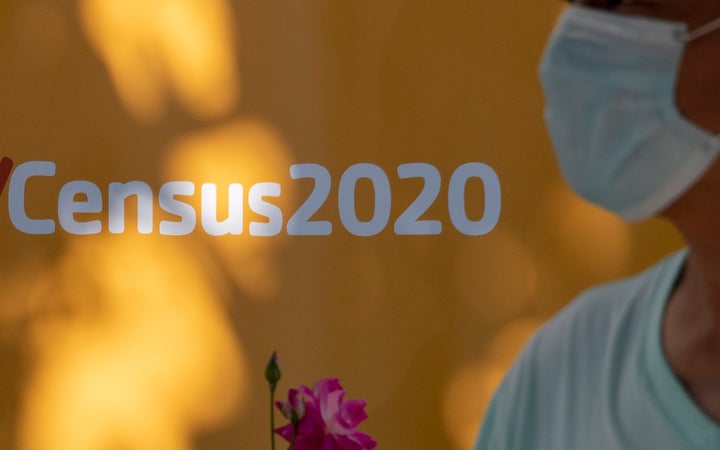 A man wearing a facemask walks past a sign encouraging people to complete the 2020 U.S. Census, in Los Angeles, California, August 10, 2020 amid the COVID-19 pandemic. (Photo by ROBYN BECK/AFP via Getty Images)