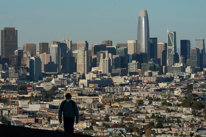 In this Dec. 7, 2020, file photo, a person wearing a protective mask walks in front of the skyline on Bernal Heights Hill during the coronavirus pandemic in San Francisco. The first numbers from the 2020 census show southern and western states gaining congressional seats. The once-a-decade head count shows where the population grew during the past 10 years and where it shrank. (AP Photo/Jeff Chiu, File)