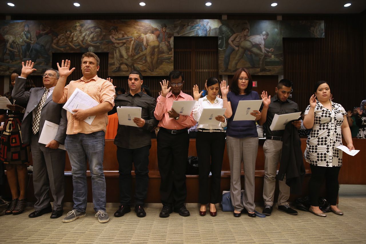 Immigrants take the oath of allegiance during a citizenship ceremony in New York City in 2013 in front of Edward Laning's mural, "The Role of the Immigrant in the Industrial Development of America," which was painted as part of New Deal jobs programs in 1937.