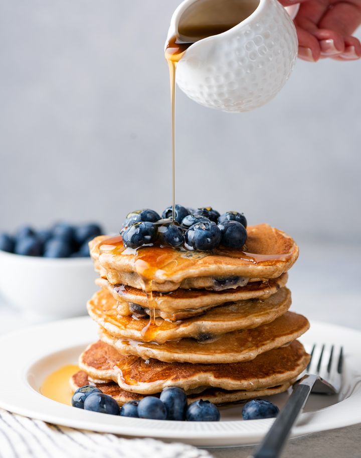 Syrup pouring on pancakes. Pancakes with blueberries and sweet syrup