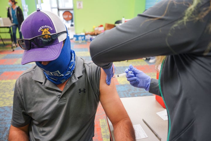 A health care worker vaccinates a man on April 30, 2021, at the Pasadena Public Library in Pasadena, Texas. (Photo by CECILE CLOCHERET/AFP via Getty Images)