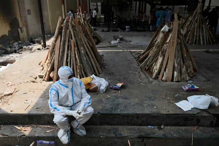 インド・ガジプールの火葬場。防護服を着ているのは、火葬を待つ家族(Photo by SAJJAD HUSSAIN/AFP via Getty Images)