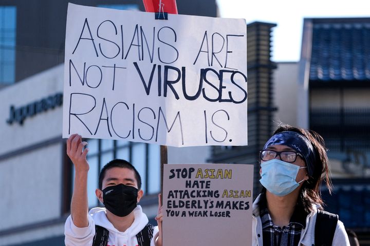 Demonstrators wearing face masks and holding signs take part in the rally "Love Our Communities: Build Collective Power" to r