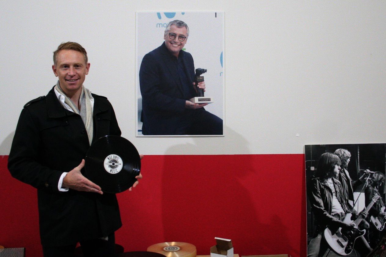 Liam Robinson, socio de Mad Vinyl Music, junto a un póster de su padre, Michael Robinson, socio fundador de la compañía, en Madrid.
