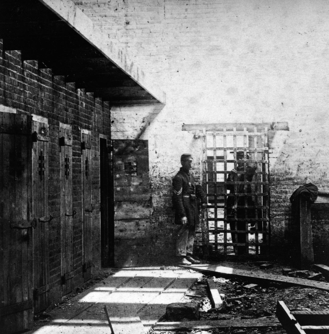 Two soldiers stand beside cells where enslaved Black people were confined in Alexandria, Virginia, circa 1861.