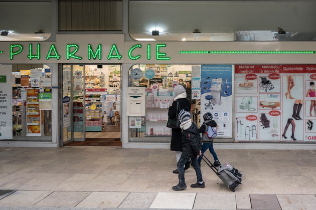 Une famille passant devant une pharmacie, quartier de La Défense, 15 mars 2021 à Puteaux. (Photo by Eric BERACASSAT/Gamma-Rapho via Getty Images)