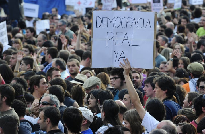 Un joven sujeta un cartel que dice "Democracia real ya" durante una protesta del 15-M en la Puerta del Sol el 21 de mayo de 2011.