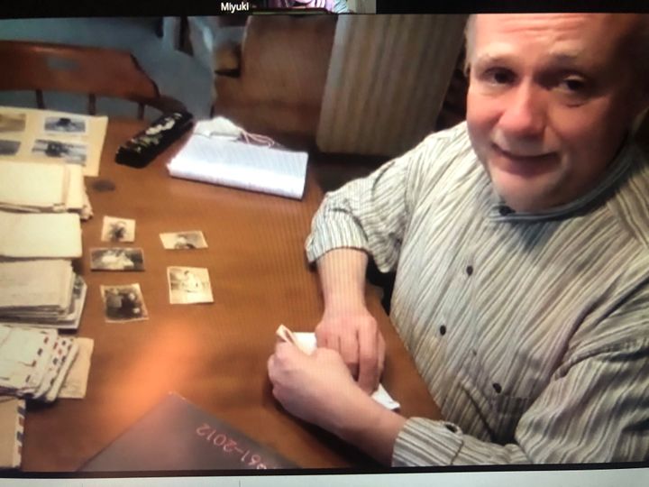 オンラインでの取材に答えるデビッド・ワッセルさん＝2021年5月9日。手前にある5枚の写真はハリーさんが戦地で拾ったもの。デビッドさんは「日本の家族のもとに返したい」という