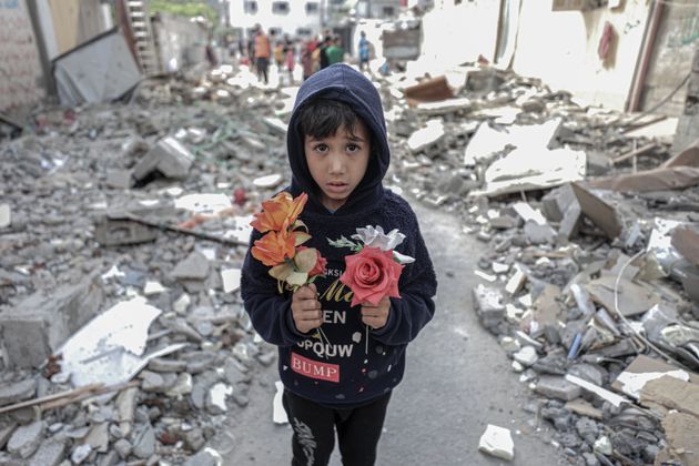 GAZA CITY, GAZA - MAY 17: A boy holds flowers among rubbles after Palestinian Al Deyri family's home...