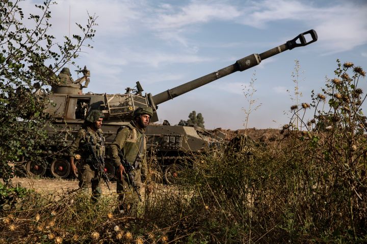 Deux soldats israéliens marchent autour d'une unité d'artillerie, à la frontière israélienne de Gaza, dimanche 16 mai 2021 (AP Photo / Heidi Levine)