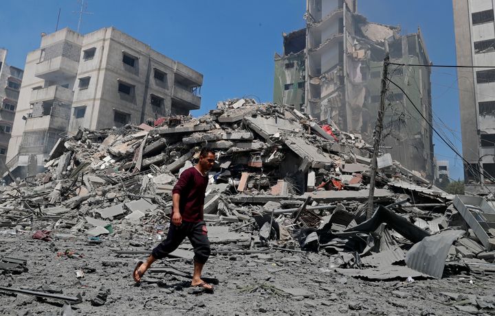 A man walks past the the rubble of the Yazegi residential building that was destroyed by an Israeli airstrike, in Gaza City, Sunday, May 16, 2021. (AP Photo/Adel Hana)