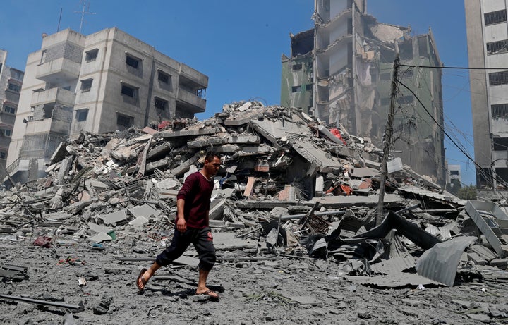 A man walks past the the rubble of the Yazegi residential building that was destroyed by an Israeli airstrike, in Gaza City,