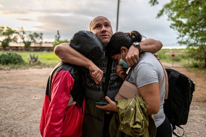 A migrant man embraces his wife and daughter after crossing the Rio Grande near the border between Mexico and the United States in Del Rio, Texas on May 16, 2021. (Photo by Sergio FLORES / AFP) (Photo by SERGIO FLORES/AFP via Getty Images)