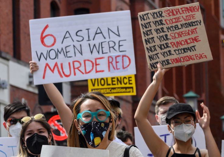 Asian women at a protest in Washington's Chinatown on March 27, 2021. One woman is holding a sign that reads "6 women were murdered." Another woman is holding a sign that reads "Not your sexual fantasy, not your docile wife, not your model minority, not your scapegoat, not your punchline, not your doormat, not your punching bag."