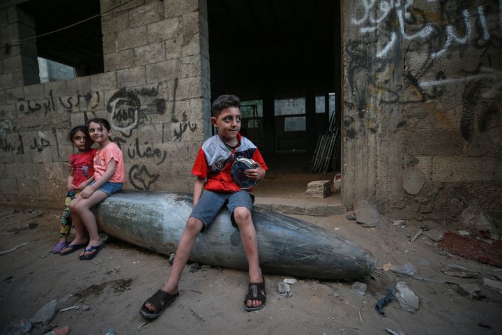 Palestinian children sit on an unexploded missile from an Israeli warplane Tuesday in the al-Rimal neighborhood of Gaza City,