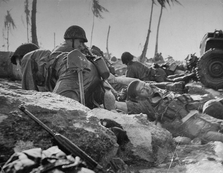 American marine dragging a dead comrade out of the surf as others duck machine gun fire from Japanese pillbox off to the left during assault on coral beachhead. (Photo by George Strock/The LIFE Picture Collection via Getty Images)