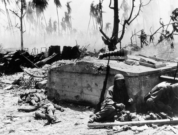 倒れた日本兵の傍らで、壁に寄りかかる米兵＝1944年2月20日ごろ、マーシャル諸島のエニウェトク環礁