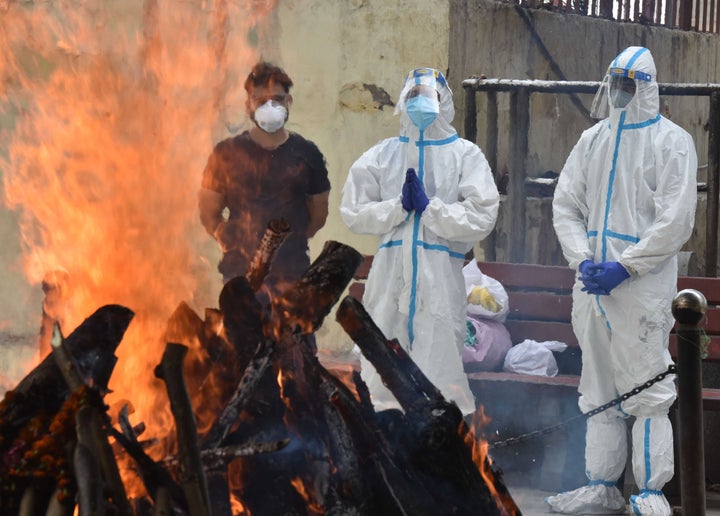Relatives wearing personal protective equipment attend the funeral of a person who died from coronavirus at a crematorium in