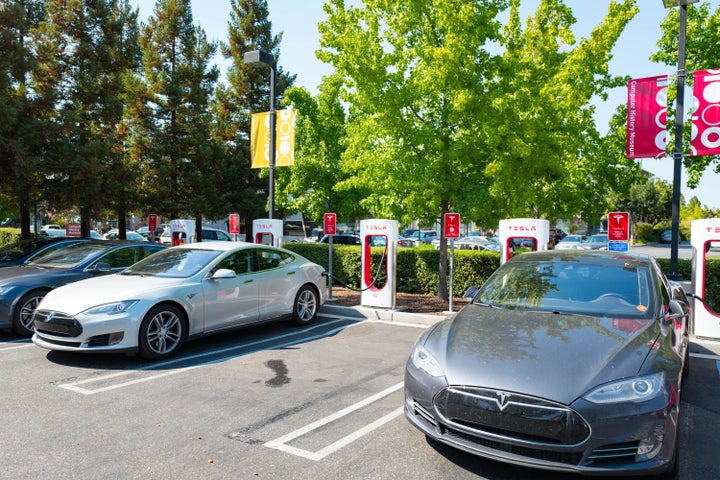 Several Tesla automobiles plugged in and charging at a Supercharger rapid battery charging station for the electric vehicle c