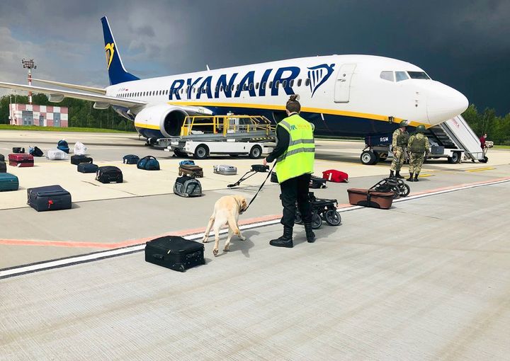 Φωτογραφία από την ONLINER. Άνδρας της ασφάλειας του αεροδρομίου με εκπαιδευμένο σκύλο, κάνει έρευνα στις αποσκευές επιβατών της πτήσης τη Ryanair, που πέταξε από την Αθήνα για το Βίλνιους αλλά δεν έφτασε στον προορισμό της...(ONLINER.BY via AP)
