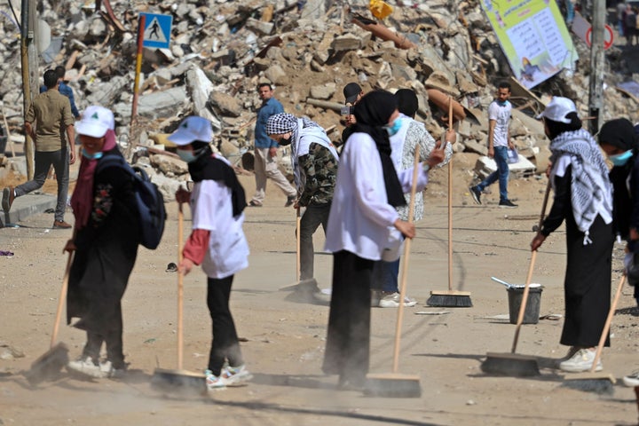 Palestinian volunteers sweep the rubble of buildings, recently destroyed by Israeli strikes, in Gaza City's Rimal district on May 25, 2021.