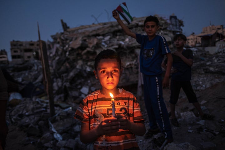 Palestinian children hold candles during a vigil Tuesday amid the ruins of houses in Beit Lahia, Northern Gaza Strip. Gaza re