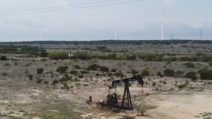 Blades from wind turbines rotate in a field behind an out-of-use oil pumpjack last month near Eldorado, Texas.