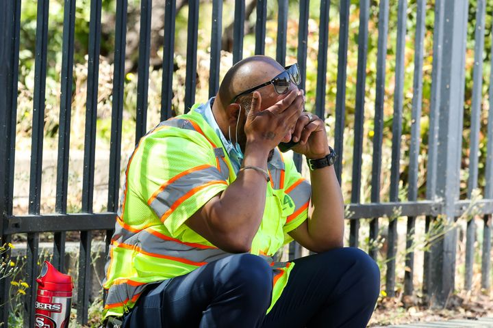 A man cries while sitting on the sidewalk near the scene of a mass shooting at the Valley Transportation Authority's (VTA) light-rail facility in San Jose, Calif., on Wednesday.
