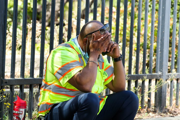 A man cries while sitting on the sidewalk near the scene of a mass shooting at the Valley Transportation Authority's (VTA) li