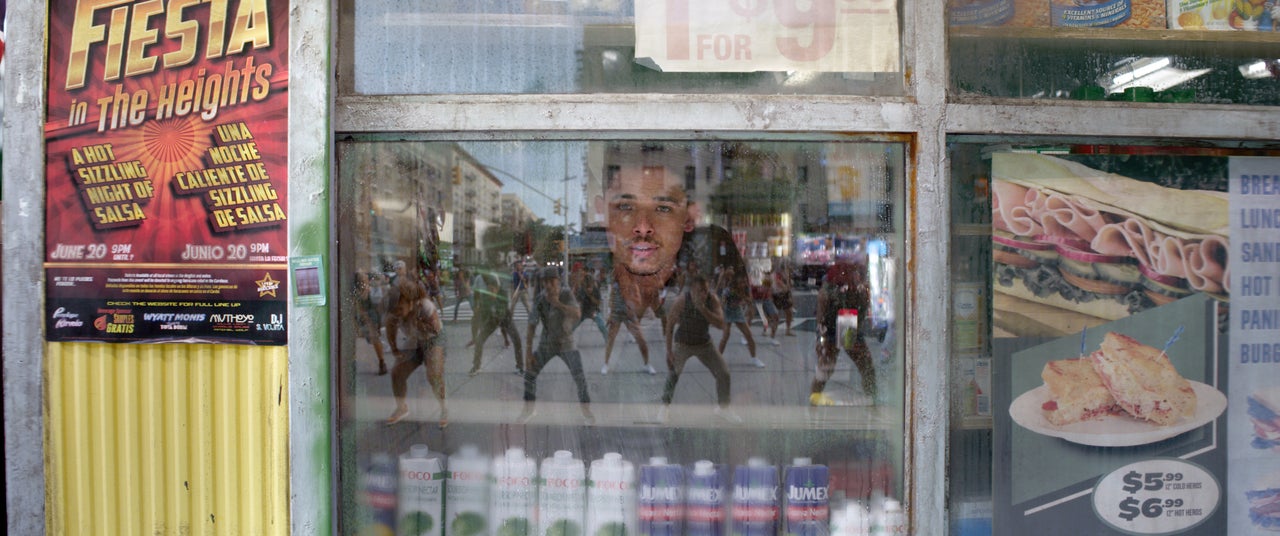 Usnavi (Anthony Ramos) looks through the window of his bodega in a scene from "In the Heights."
