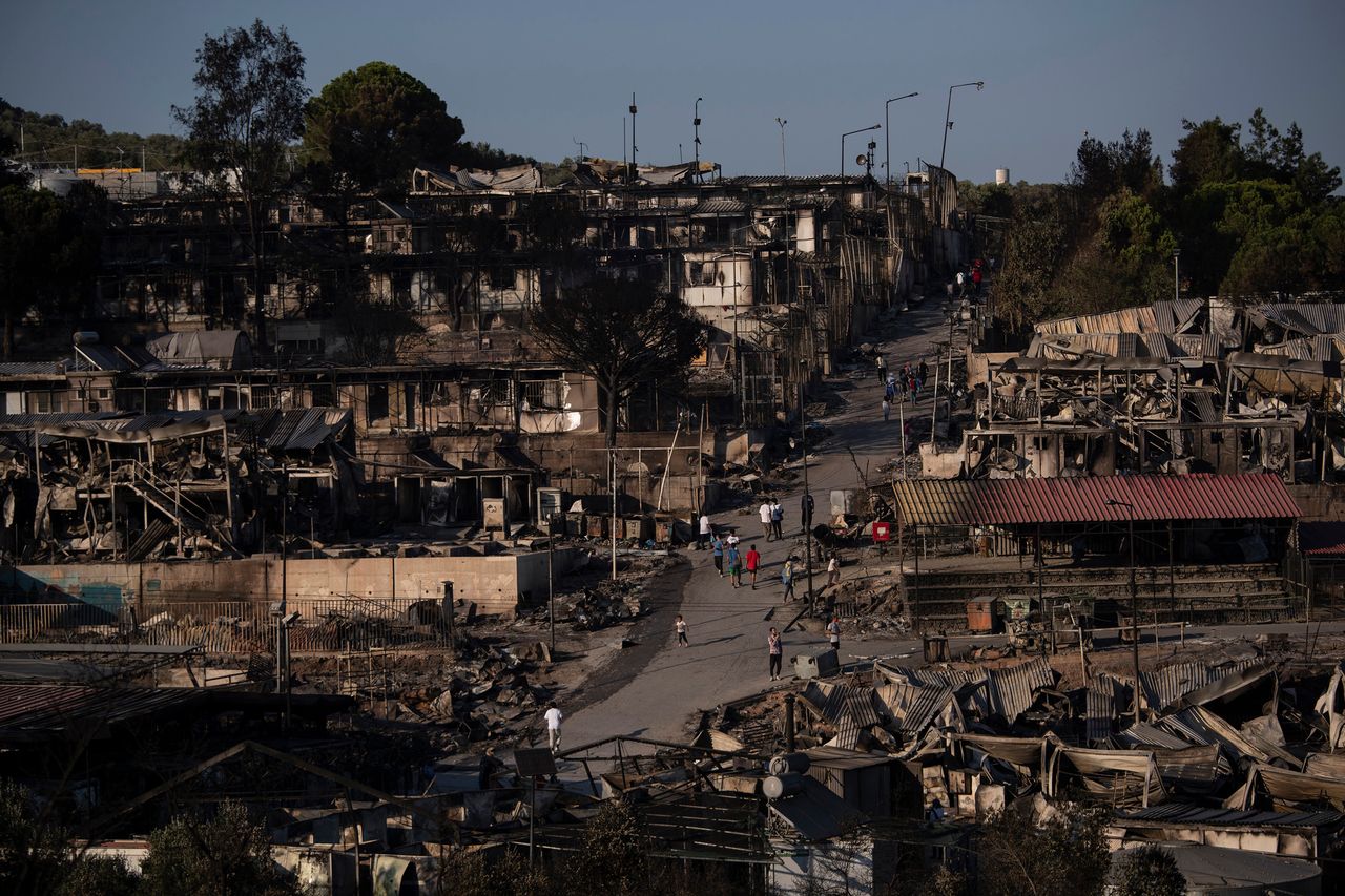 Πρόσφυγες και μετανάστες περπατούν στον κατεστραμμένο από τη φωτιά καταυλισμό της Μόριας, 9 Σεπτεμβρίου 2020