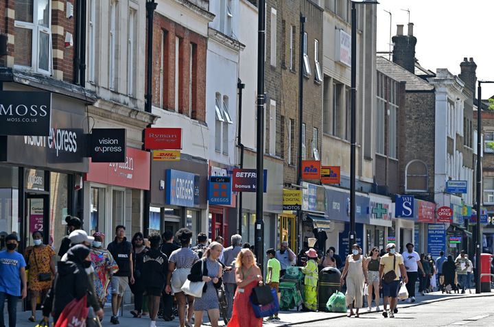 Pedestrians, some wearing face covering due to Covid-19, walk past shops in Hounslow, west London on June 1, 2021.