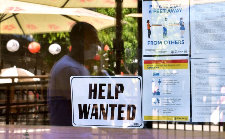 A 'Help Wanted' sign is posted beside Coronavirus safety guidelines in front of a restaurant in Los Angeles, California on May 28, 2021.