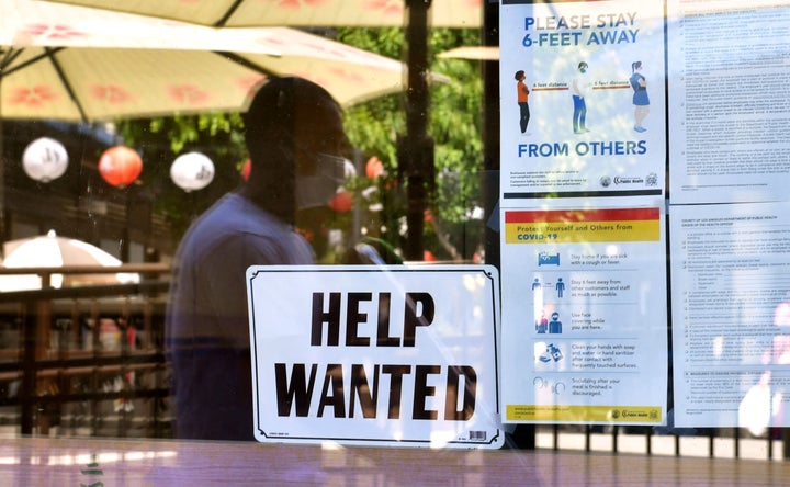 A 'Help Wanted' sign is posted beside Coronavirus safety guidelines in front of a restaurant in Los Angeles, California on May 28, 2021.