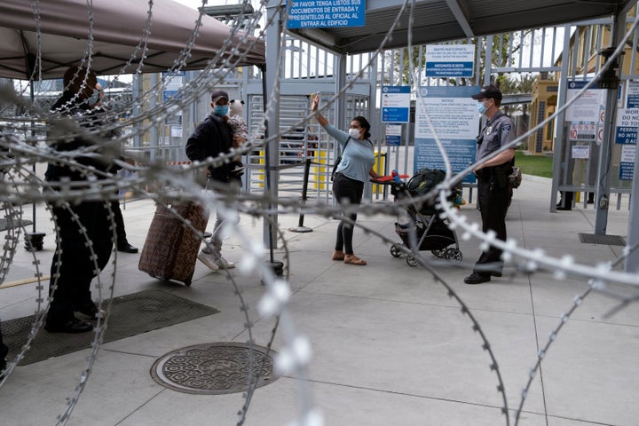 An asylum seeker waves goodbye a she enters the United States at a port of entry.