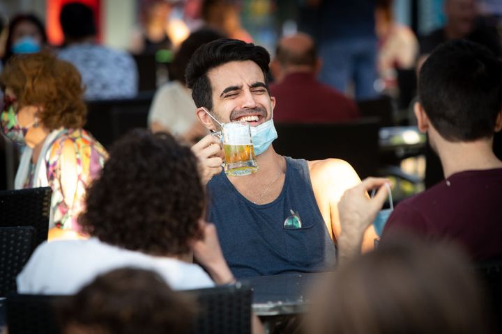Un hombre sonríe mientras se toma una cerveza en una terraza española