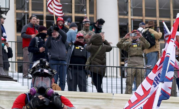 Russ Taylor (middle, in MAGA hat) on the west side of the Capitol during the attack. Another likely defendant, wearing a similar patch, appears on the right.